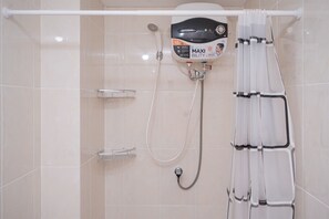 Un baño moderno con ducha, cabezal de ducha de mano y panel de control en la pared.