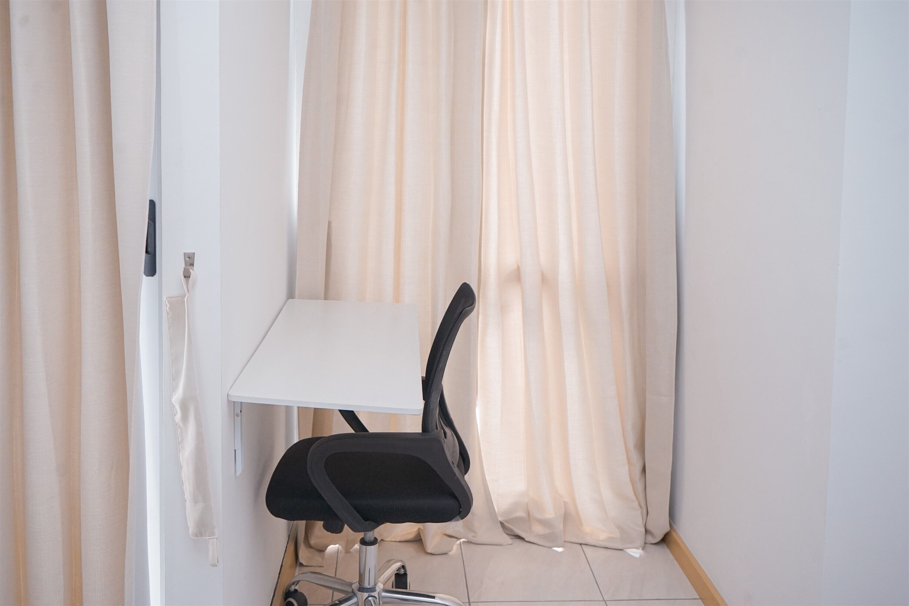 A small room with a white table and a black office chair.