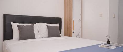 A neatly made bed with a black headboard, white bedding, and a blue accent.