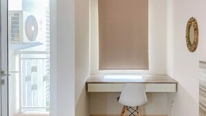 Ein Zimmer mit Schreibtisch, Stuhl, einem Fenster mit Jalousien und einer Wand-Klimaanlage.