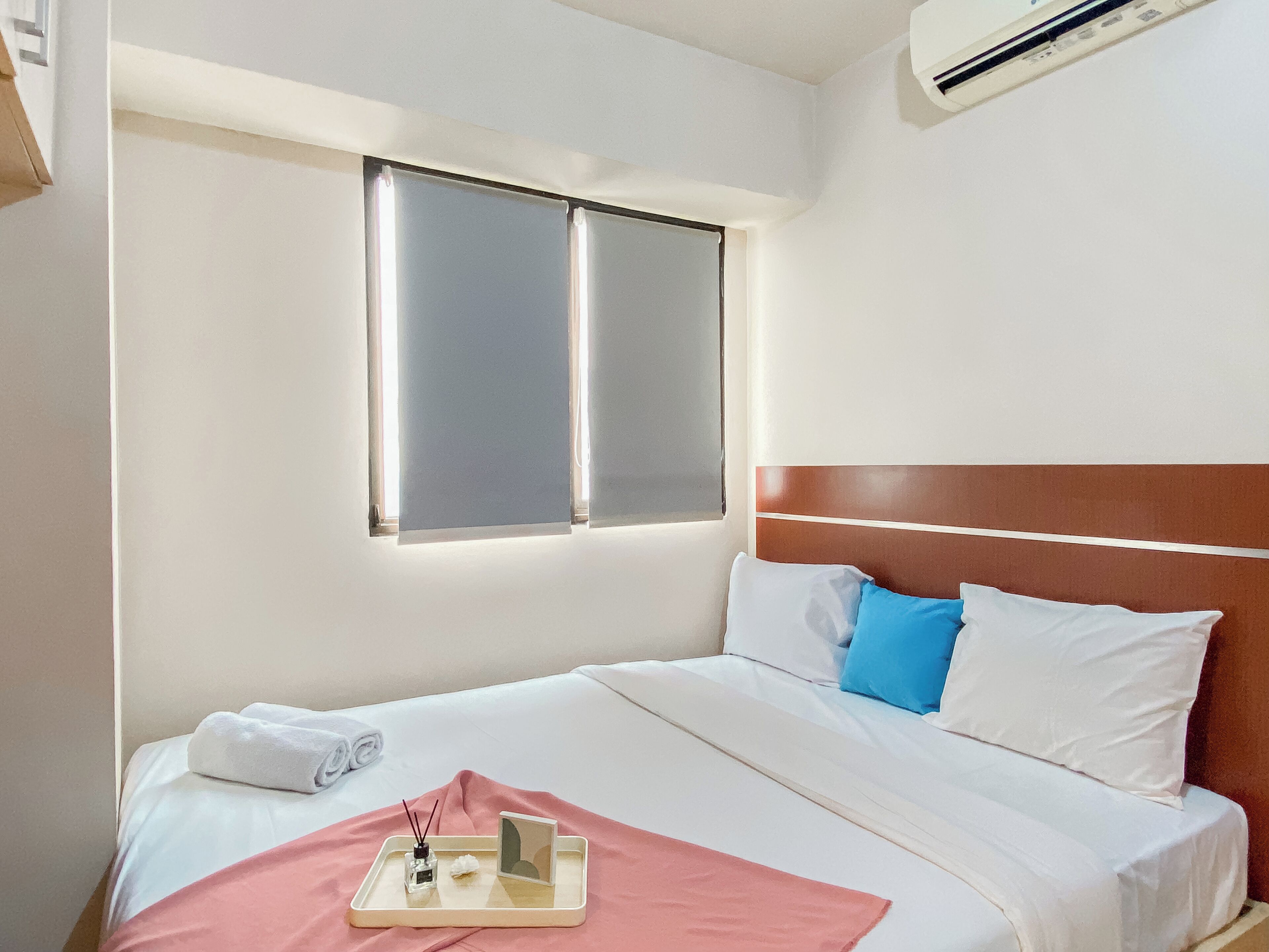 A hotel room with a bed, a window, and an air conditioning unit.