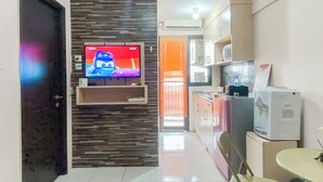 A modern kitchen with a built-in TV, a dining area with a table and chairs, and a kitchen counter with appliances. - Good Place 2Br At Kebagusan City Apartment (Jakarta)