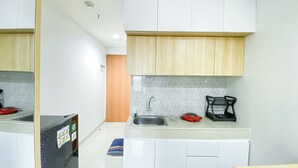 A compact kitchen with white cabinets, a tiled backsplash, and a sink. - Nice And Comfy Studio At Evenciio Margonda Apartment (Depok)
