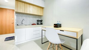 A modern kitchen with white cabinets, a wooden countertop, a sink, and a travel bag on the counter. - Nice And Comfy Studio At Evenciio Margonda Apartment (Depok)