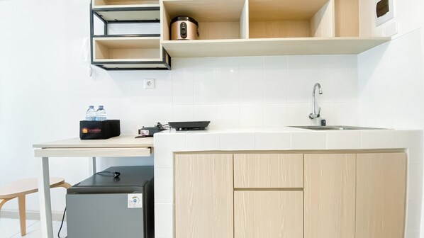 Une cuisine moderne avec un évier, un plan de travail et des placards en bois. On peut voir un sac de voyage sur la table et un petit appareil électroménager sous le plan de travail.