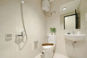 A bathroom with a toilet, a sink, a shower, and a mirror. - Best Furnished And Homey Studio Nifarro Park Apartment (Jakarta)