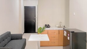 A compact kitchen with a refrigerator, sink, and a small dining table with a plant. - Best Furnished And Homey Studio Nifarro Park Apartment (Jakarta)