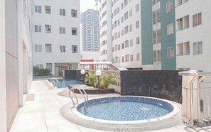 Un immeuble résidentiel doté d’une piscine, d’un espace extérieur aménagé et d’une zone couverte avec des plantes.
