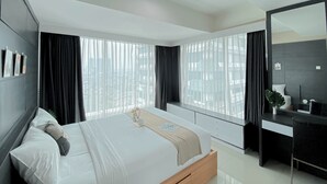 A modern bedroom with a large bed, a bedside desk, and a large window with curtains. - Nice And Elegant 2Br At Grand Kamala Lagoon Apartment (Bekasi)