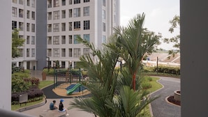 Un edificio residenziale con un'area giochi e una palma in primo piano.