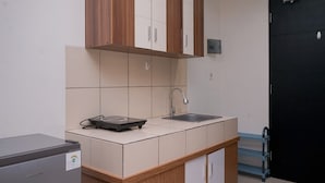 A compact kitchen with a refrigerator, a sink, and wooden cabinets.