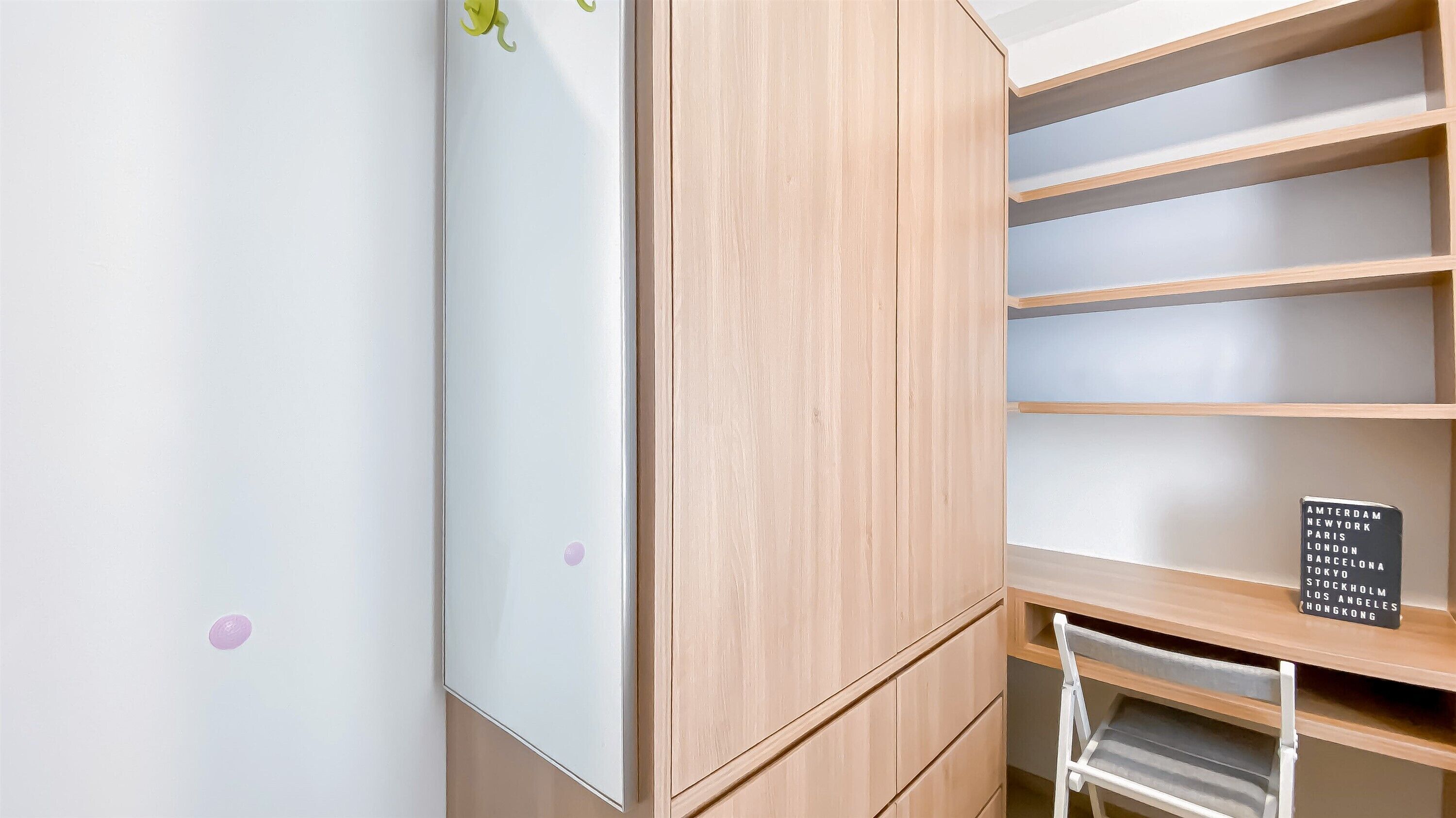 A room with a white wall, a wooden cabinet with multiple shelves, and a sign listing cities.