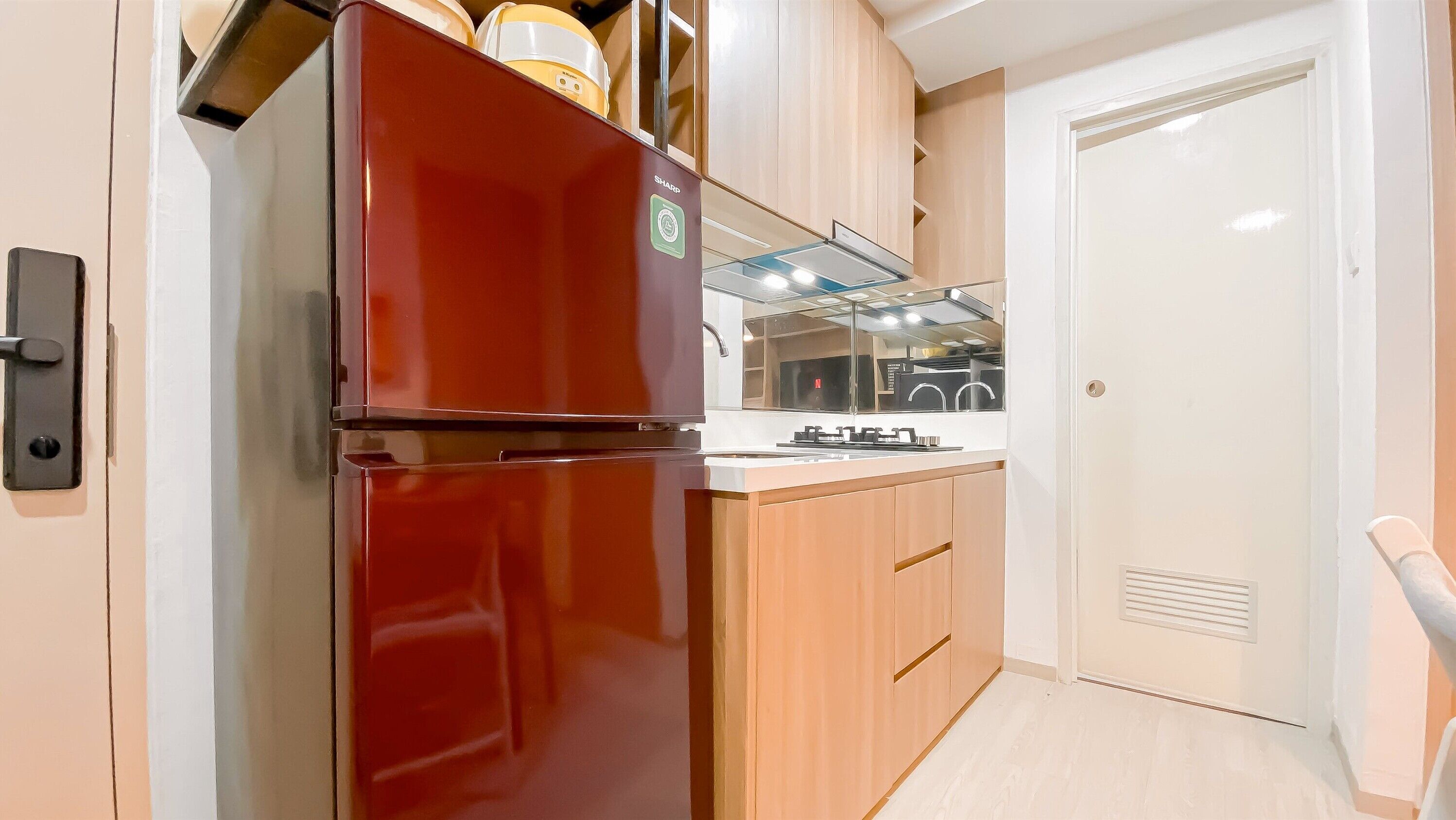 Una cocina compacta con un refrigerador rojo, armarios de madera y una encimera blanca.