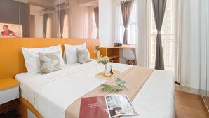 Una habitación de hotel con cama, escritorio y ventana con cortinas.