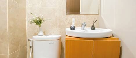 A bathroom with a toilet, sink, and mirror.