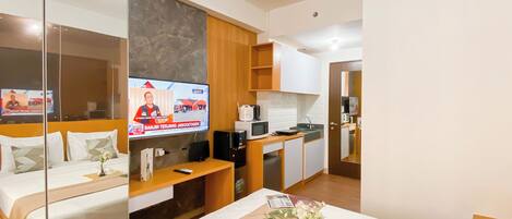 A hotel room with a bed, a TV, a small kitchenette, and a bathroom.