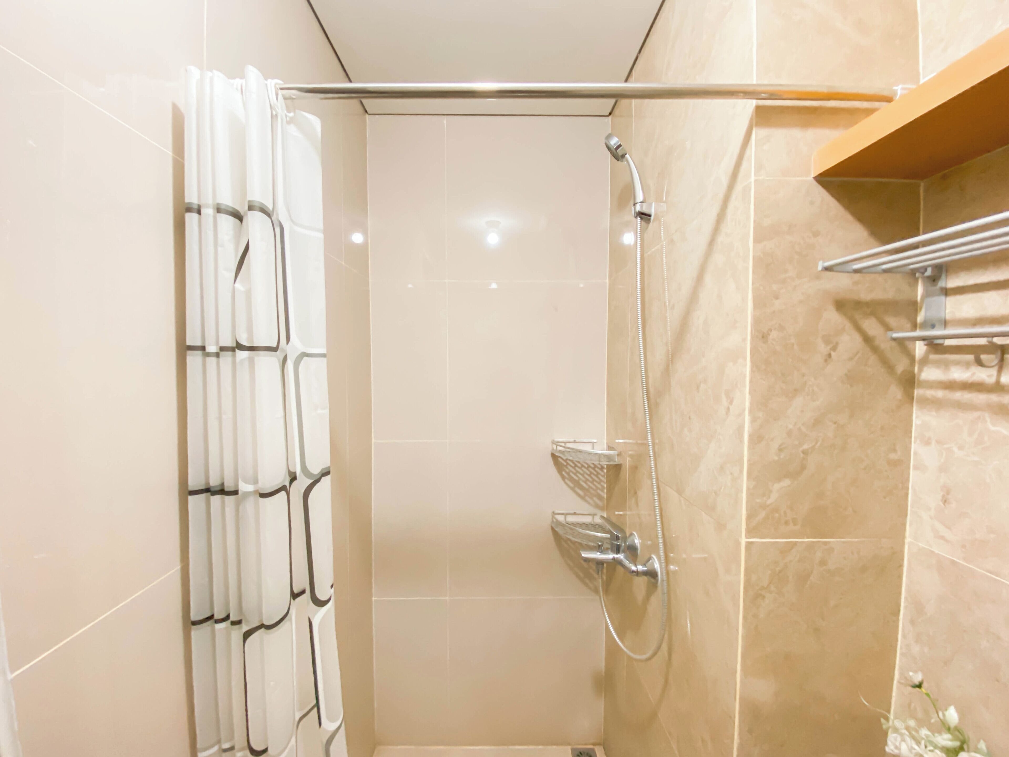 A shower area with a glass door, a handheld showerhead, and a wall-mounted towel rack.
