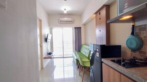 A modern kitchen with a built-in stove, a green sofa, and a flat-screen TV.