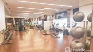 A spacious gym with various exercise equipment, including treadmills, stationary bikes, and weight machines.