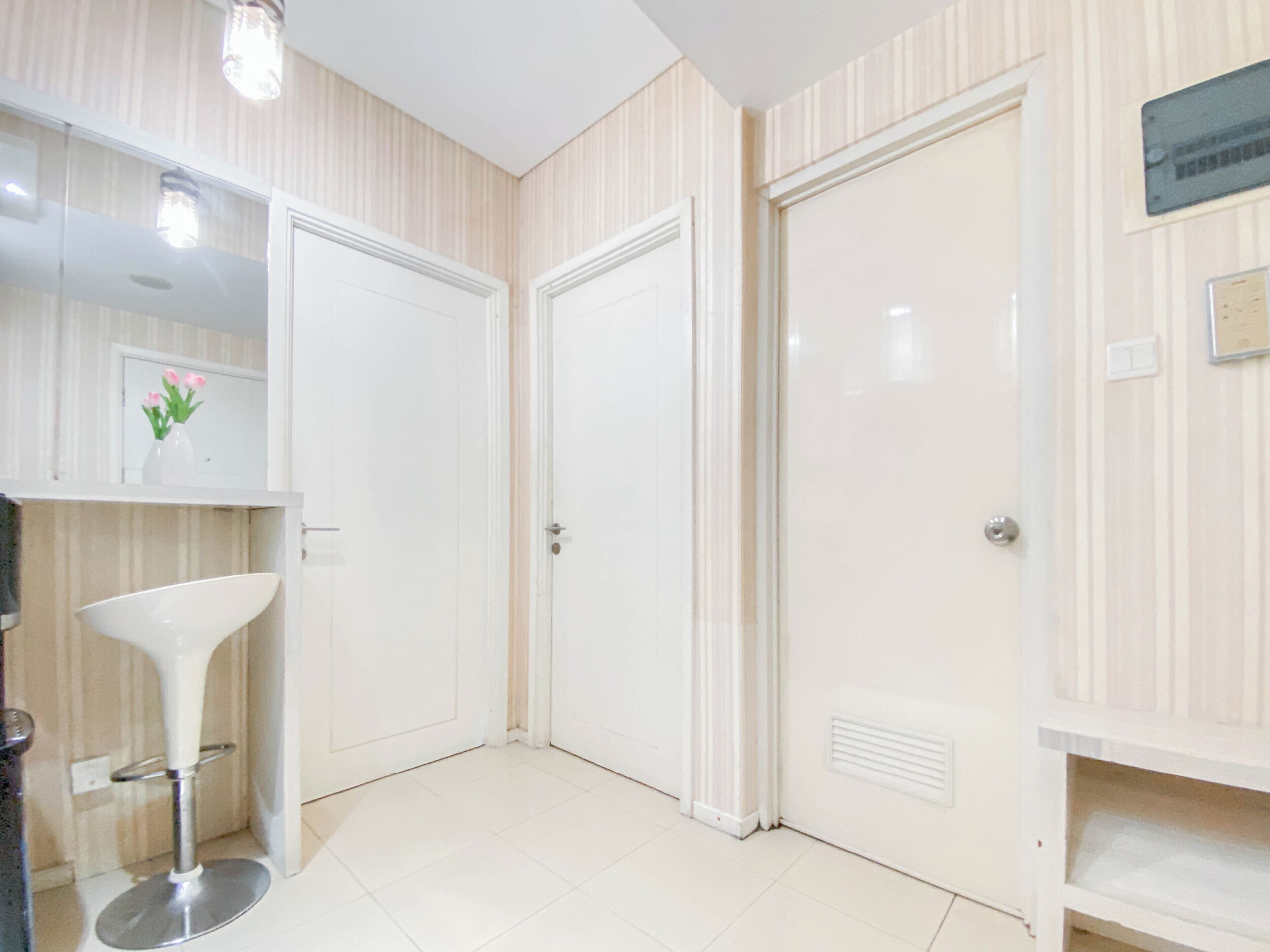 A clean, modern bathroom with white tiles, a white pedestal sink, and two white doors.