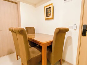 Un coin repas avec une table en bois et quatre chaises rembourrées.