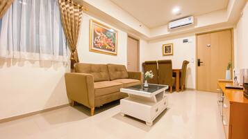 A living room with a sofa, coffee table, and a dining area with chairs and a table.