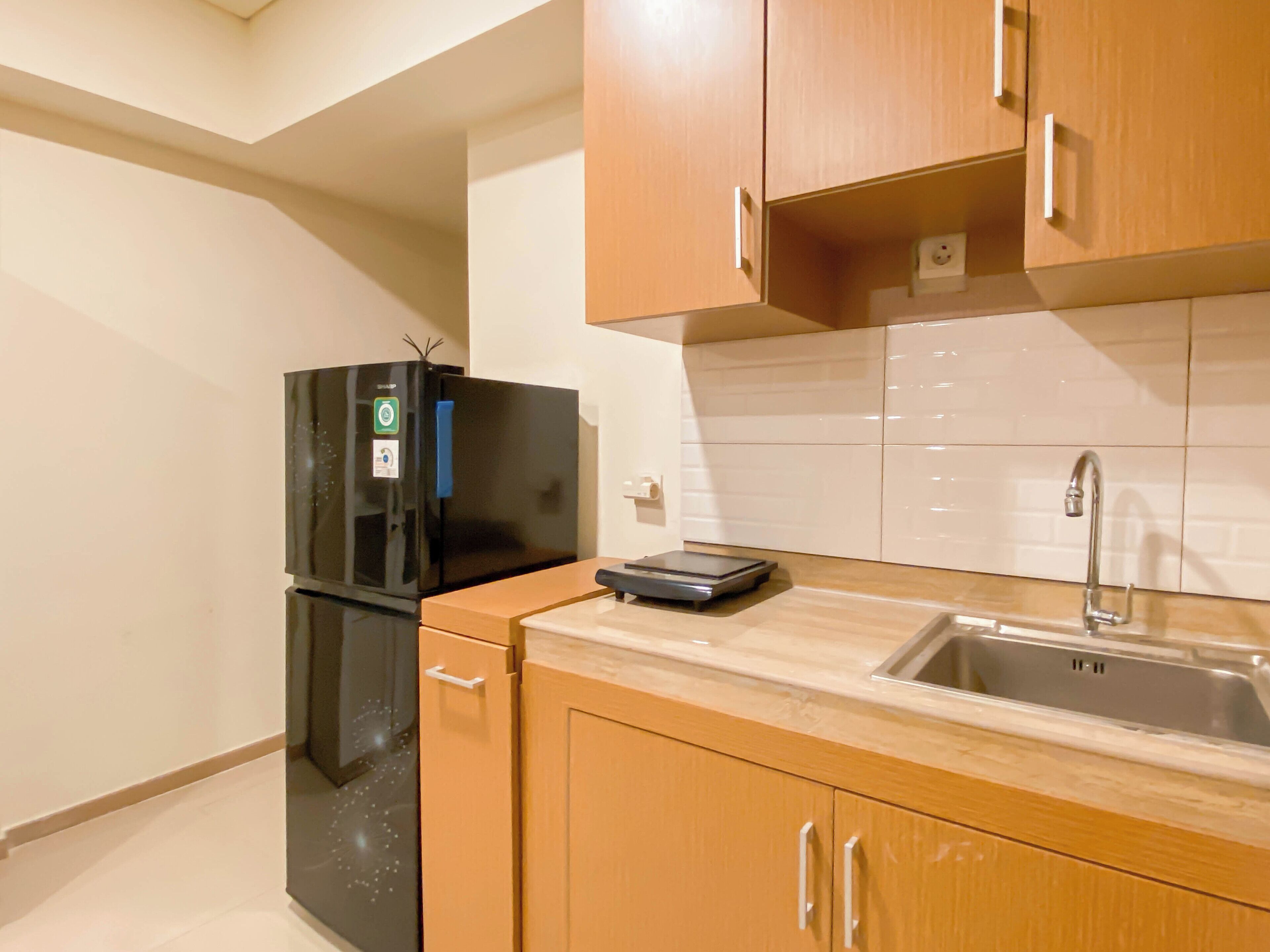 A compact kitchen with wooden cabinets, a black refrigerator, a built-in sink, and a scale on the countertop.