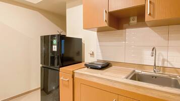 A compact kitchen with wooden cabinets, a black refrigerator, a built-in sink, and a scale on the countertop.