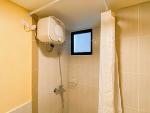 Une salle de bain avec une douche, un rideau blanc et une petite fenêtre.