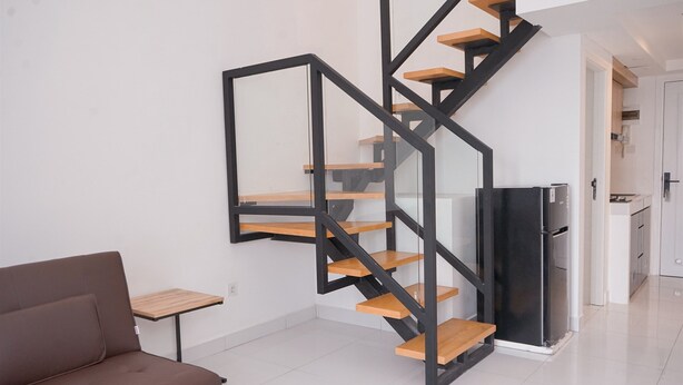 A modern living space with a black metal staircase, a brown sofa, and a small wooden table.