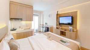A modern hotel room with a bed, a TV, a kitchenette, and a bathroom. - Well Furnished Studio Apartment At Cinere Resort (Depok)