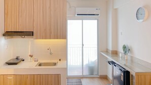 A modern kitchen with wooden cabinets, a built-in oven, a sink, and a dishwasher. - Well Furnished Studio Apartment At Cinere Resort (Depok)