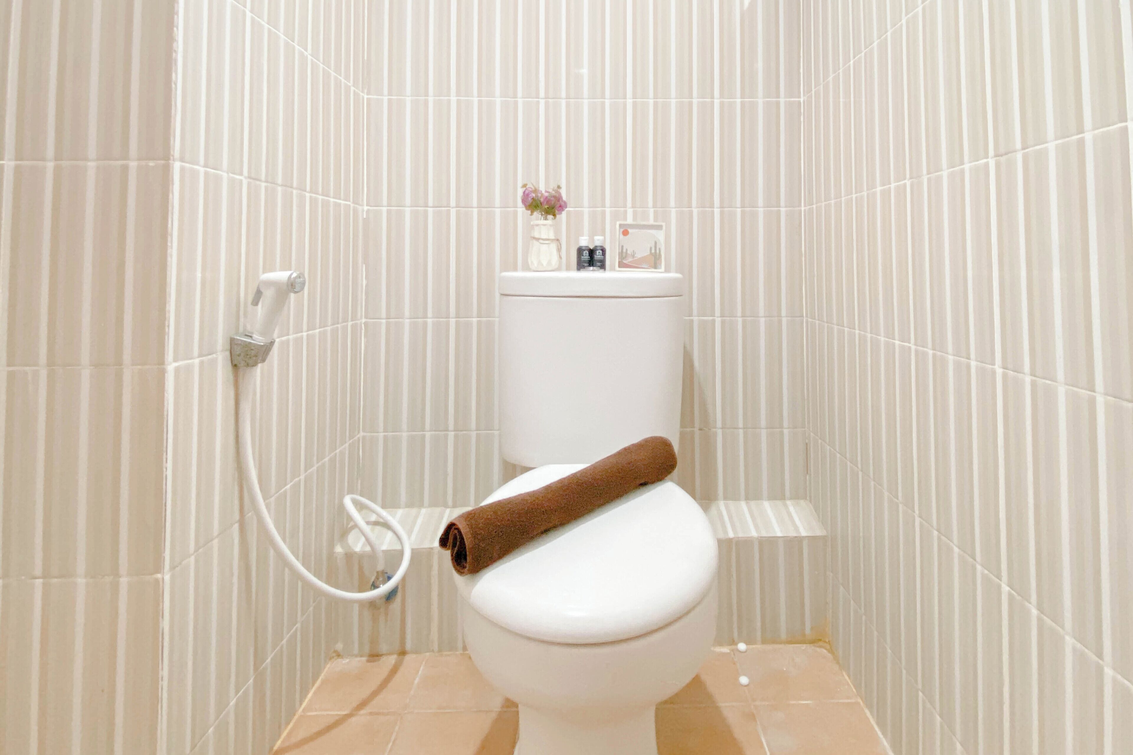 A bathroom with a toilet, a towel, and a small shelf with toiletries.