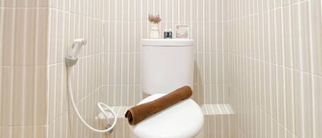 A bathroom with a toilet, a towel, and a small shelf with toiletries.