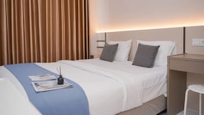 A hotel room with a neatly made bed, a bedside table, and a lamp.