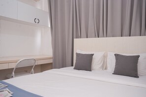 A bedroom with a bed, two pillows, a desk, and a chair. - Comfy And Minimalist 2Br At Asatti Apartment (Pagedangan)