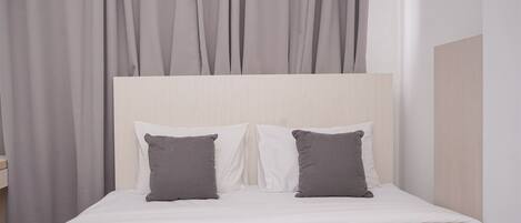 A bed with a wooden headboard, two pillows, and a white bedspread.