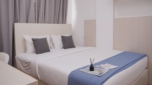 A neatly arranged hotel room with a bed, a bedside table, and a chair.