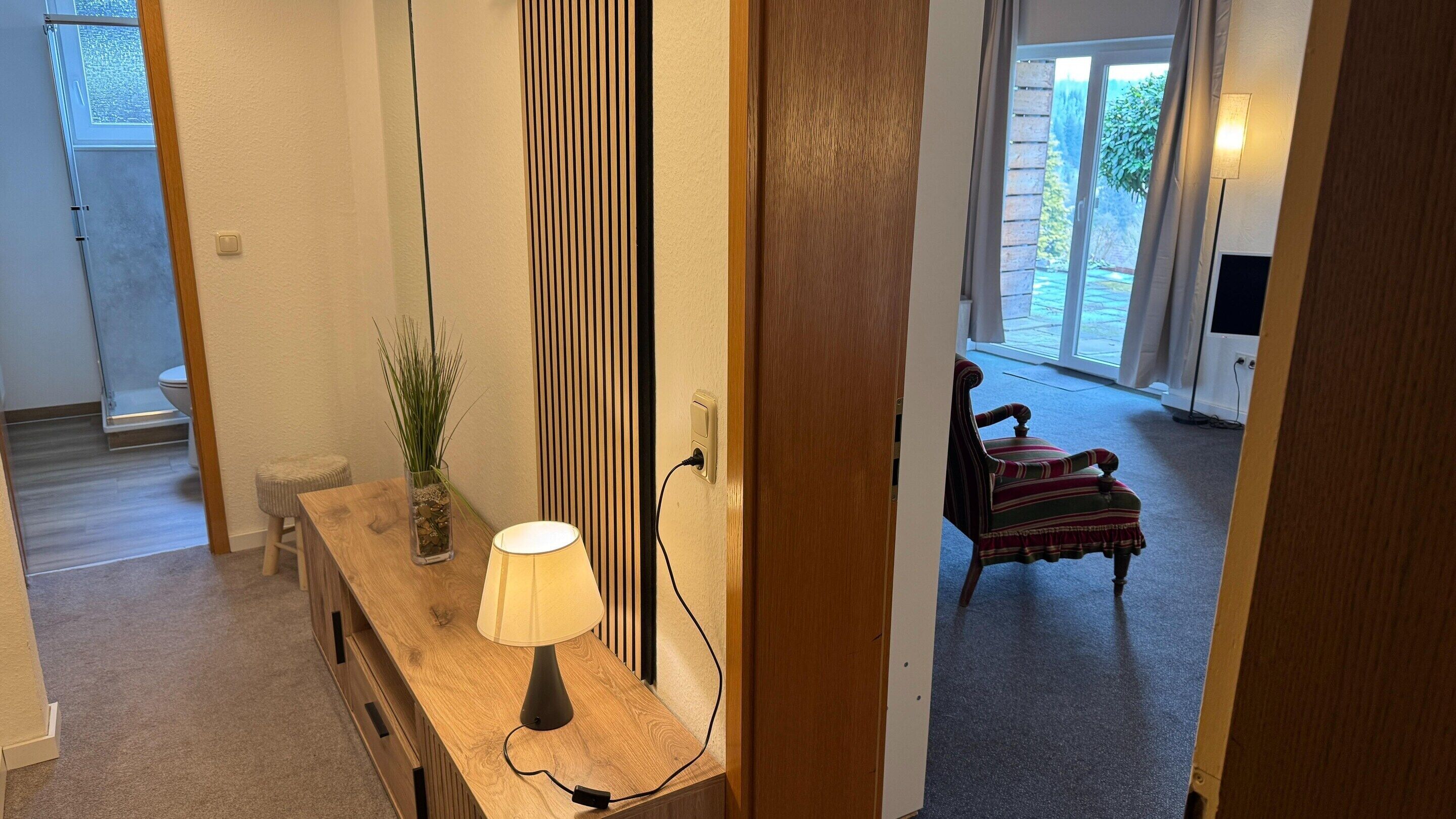 A hallway with a wooden bench, a lamp, and a potted plant.