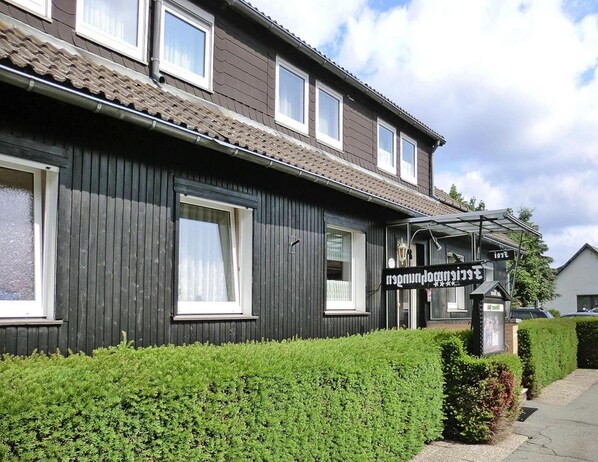 A two-story building with a dark facade, multiple windows, and a covered outdoor seating area. - Apartment for 4 Guest Near Harz Mountains (Clausthal-Zellerfeld)