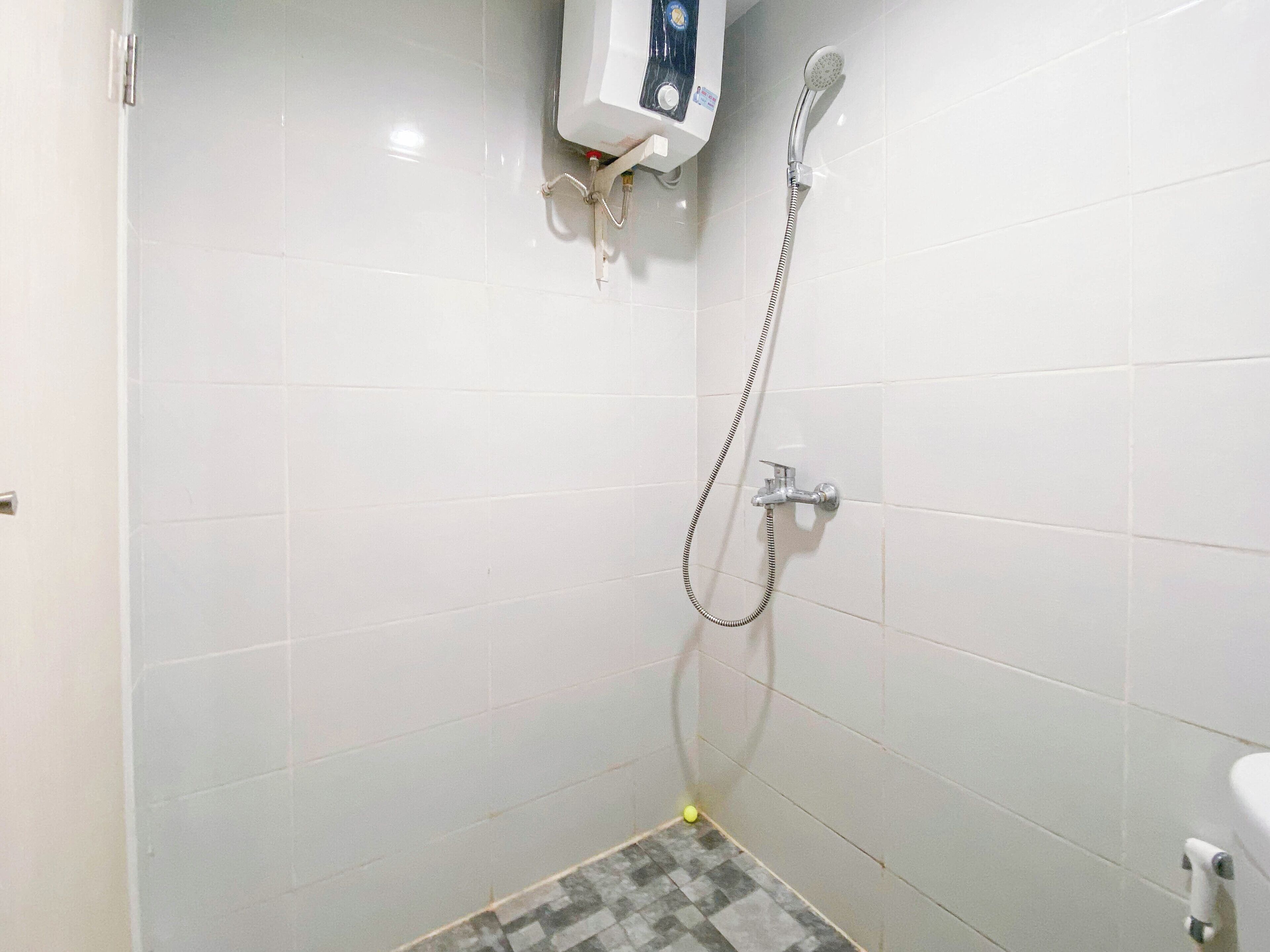 Un baño pequeño con azulejos, ducha, inodoro y dispensador de jabón en la pared.