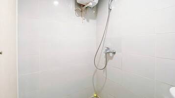 Un baño pequeño con azulejos, ducha, inodoro y dispensador de jabón en la pared.