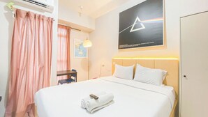 A hotel room with a bed, a desk, a chair, an air conditioner, a map on the wall, and a poster. - Great Choice Studio At Amartha View Apartment (Semarang)