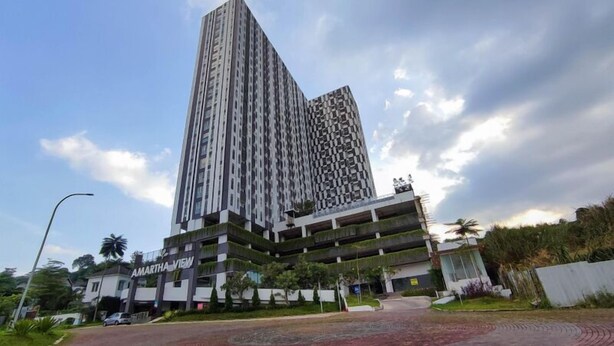 A high-rise building with a modern design, featuring a prominent entrance and a parking structure below. - Great Choice Studio At Amartha View Apartment (Semarang)