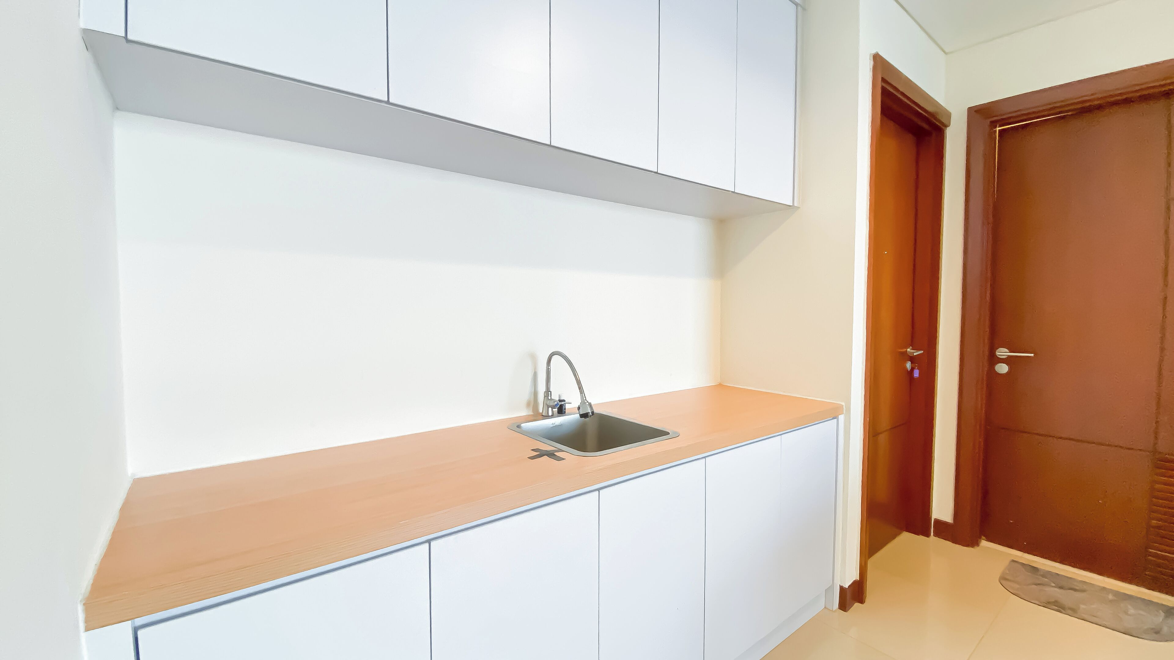 A kitchen with white cabinets, a wooden countertop, and a stainless steel sink.
