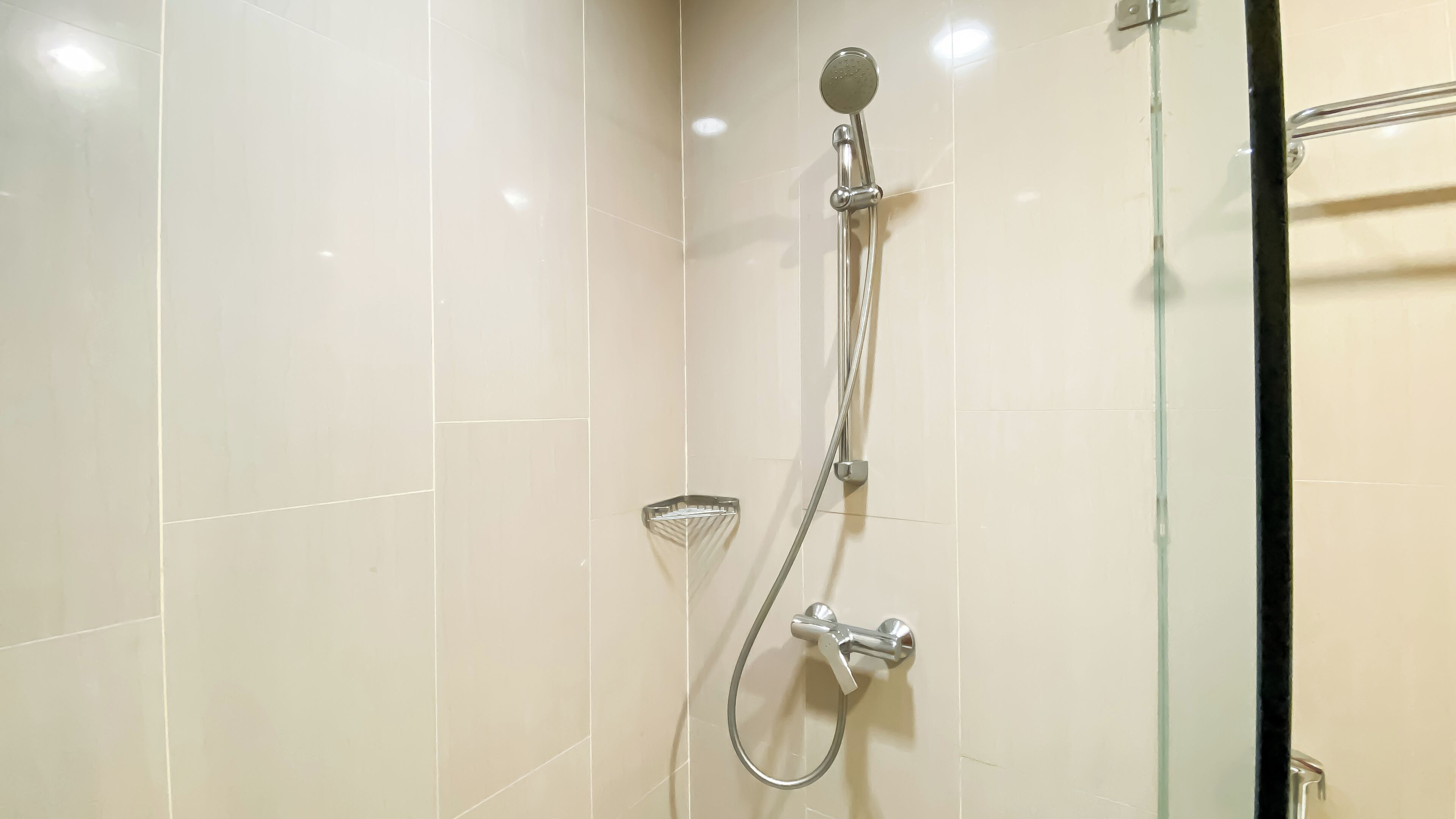 A shower with a handheld showerhead and a wall-mounted faucet.