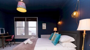 Une chambre à coucher avec un lit, des lampes de chevet, un bureau et une fenêtre.