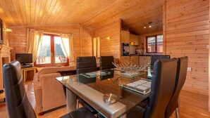 A wooden cabin interior with a dining area, kitchen, and living room. - Astbury Falls Escape – A Tranquil Stay in Nature - Pass the Keys (Bridgnorth)
