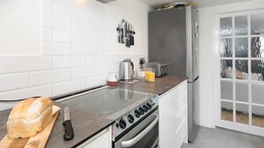 A modern kitchen with white subway tiles, a stainless steel range, a toaster, and a refrigerator.