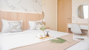 Una habitación de hotel moderna con cabecera de mármol, puerta de madera, escritorio blanco y cama con bandeja de artículos de aseo.